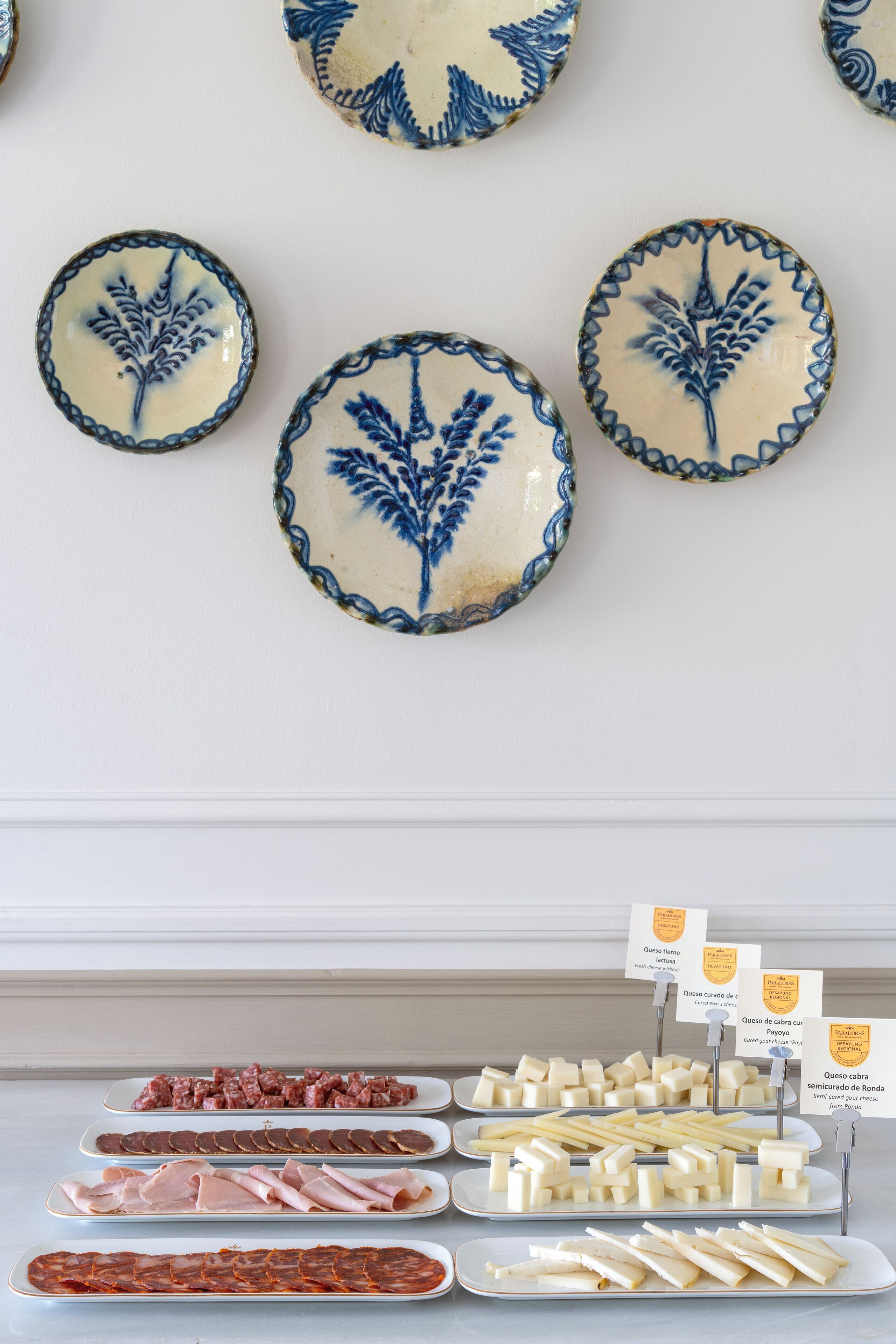 A display of various cheeses and cured meats on plates.