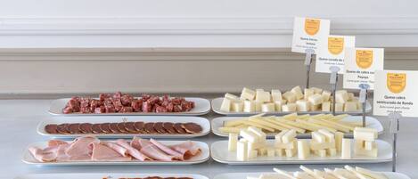 A display of various cheeses and cured meats on plates.