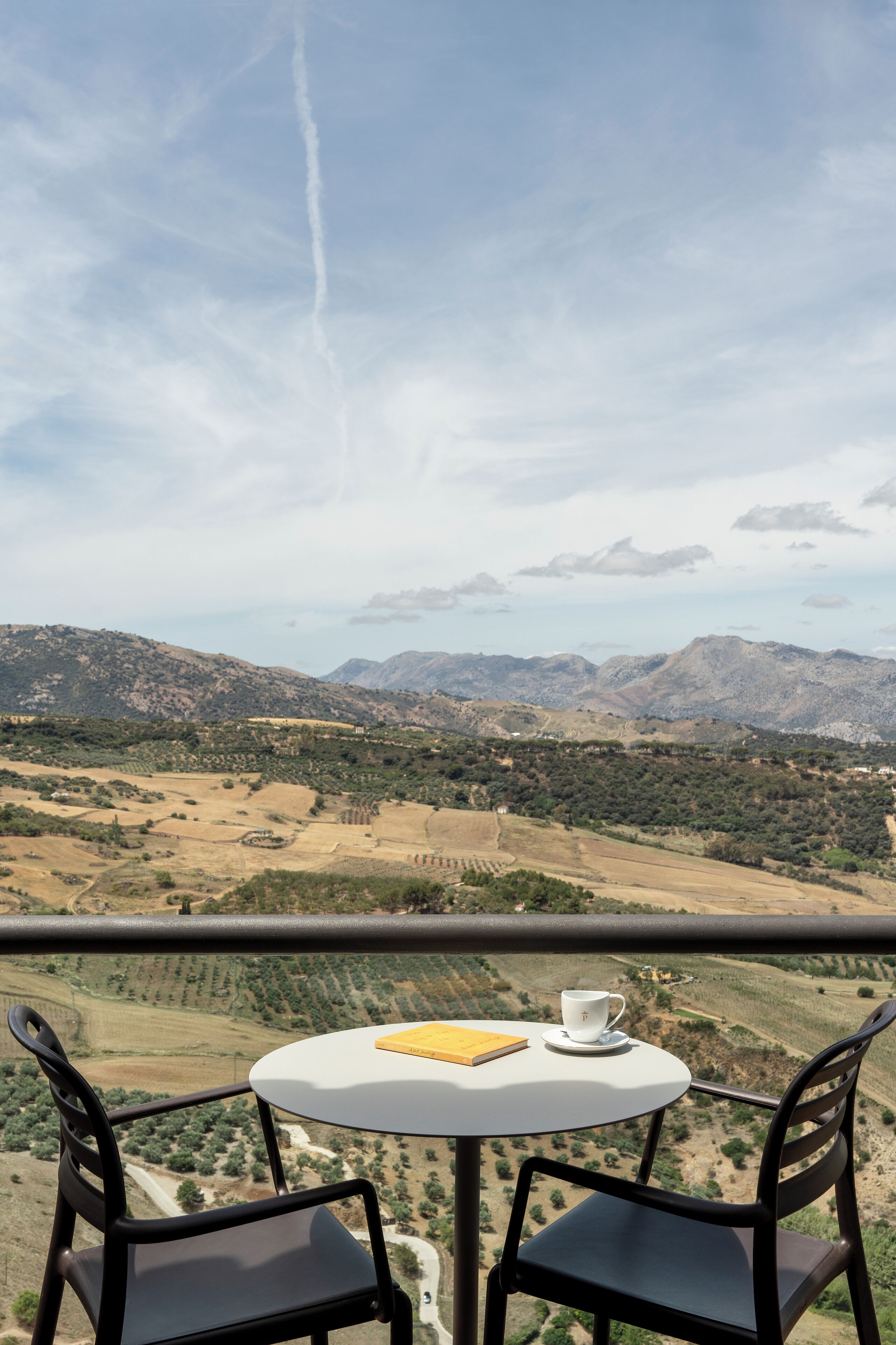 Un balcon avec une table et des chaises donnant sur un paysage montagneux.