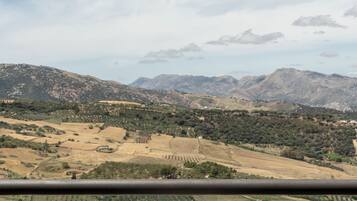 Un balcon avec une table et des chaises donnant sur un paysage montagneux.