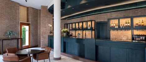A bar area with a brick wall, a counter with bottles, and a seating area with chairs.