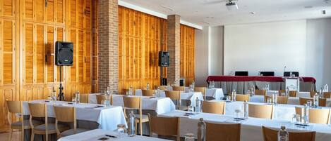 A conference room with multiple tables, chairs, and a stage area.