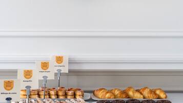 Una vitrina de pastelería con dulces y una pared decorada con platos de cerámica.