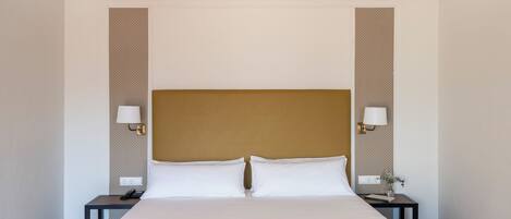 Una habitación de hotel con una cama grande, dos mesitas de noche y dos lámparas de pared.
