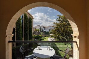 Un balcón con mesa y sillas, con vistas a un patio y edificios con vegetación.