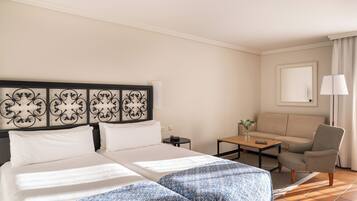 A hotel room with two beds, a sofa, a small table, and a lamp.