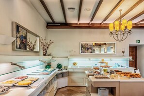 A buffet area with various food items, glass display cases, and a chandelier.