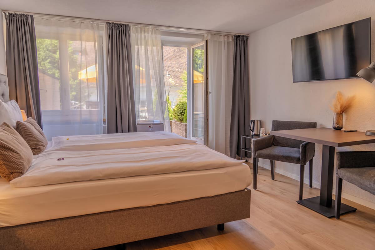 A modern hotel room with a large bed, a dining table, and a TV.