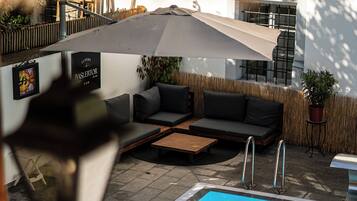 A poolside area with a sofa, umbrella, and a sign for 'Luzern Baslertor'.