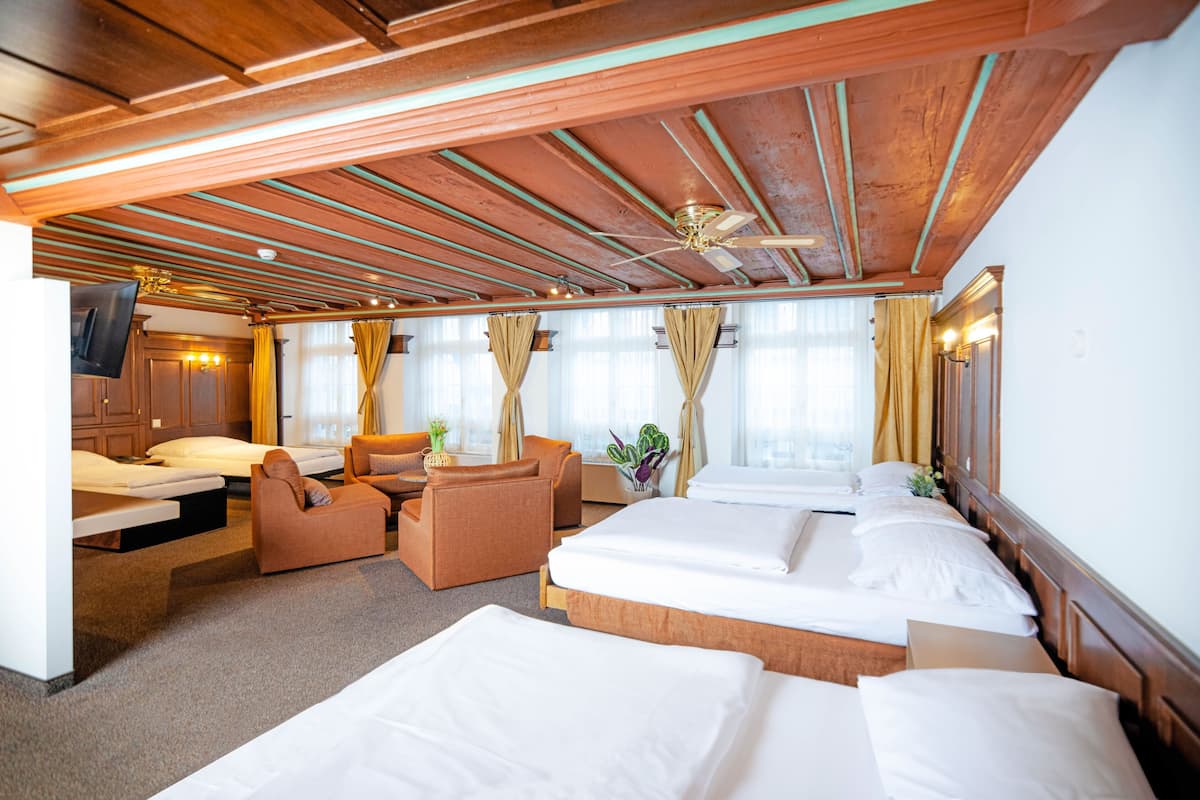 A hotel room with a wooden ceiling, a bed, a sofa, and a desk.