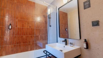 Een moderne badkamer met een grote spiegel, een witte wastafel en een douchecabine van glas.