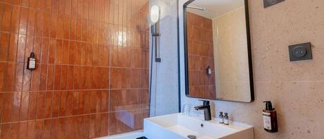A modern bathroom with a large mirror, a white sink, and a glass shower enclosure.