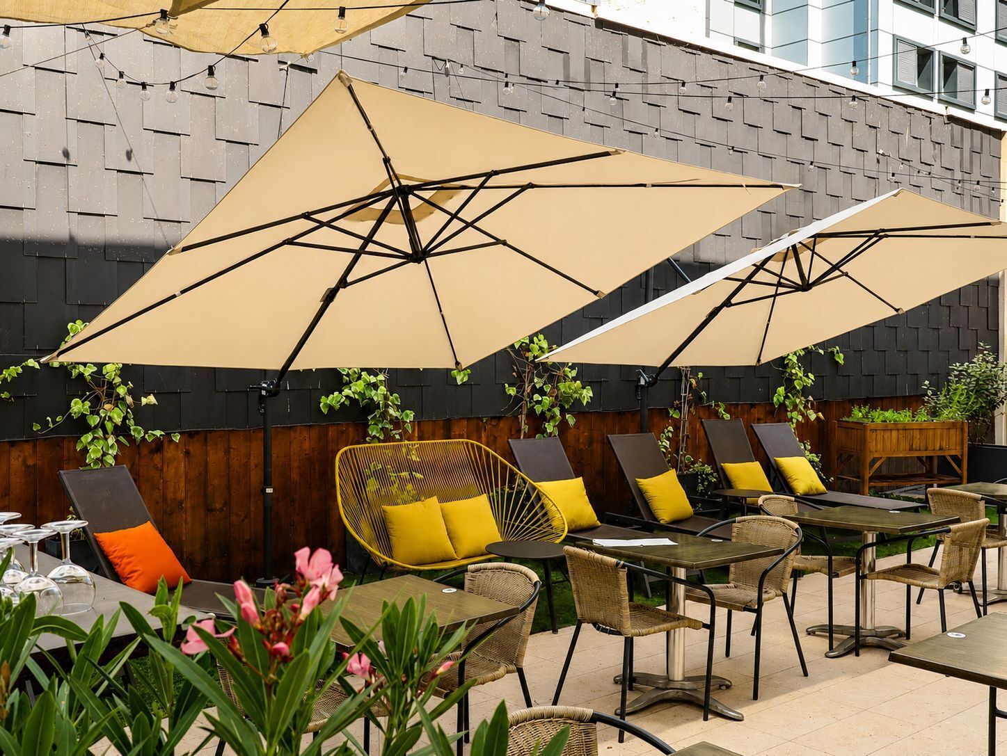 An outdoor seating area with tables and chairs, umbrellas, and plants.