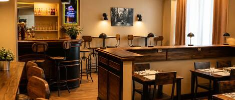 A bar area with stools, a counter with bottles, and a television screen.