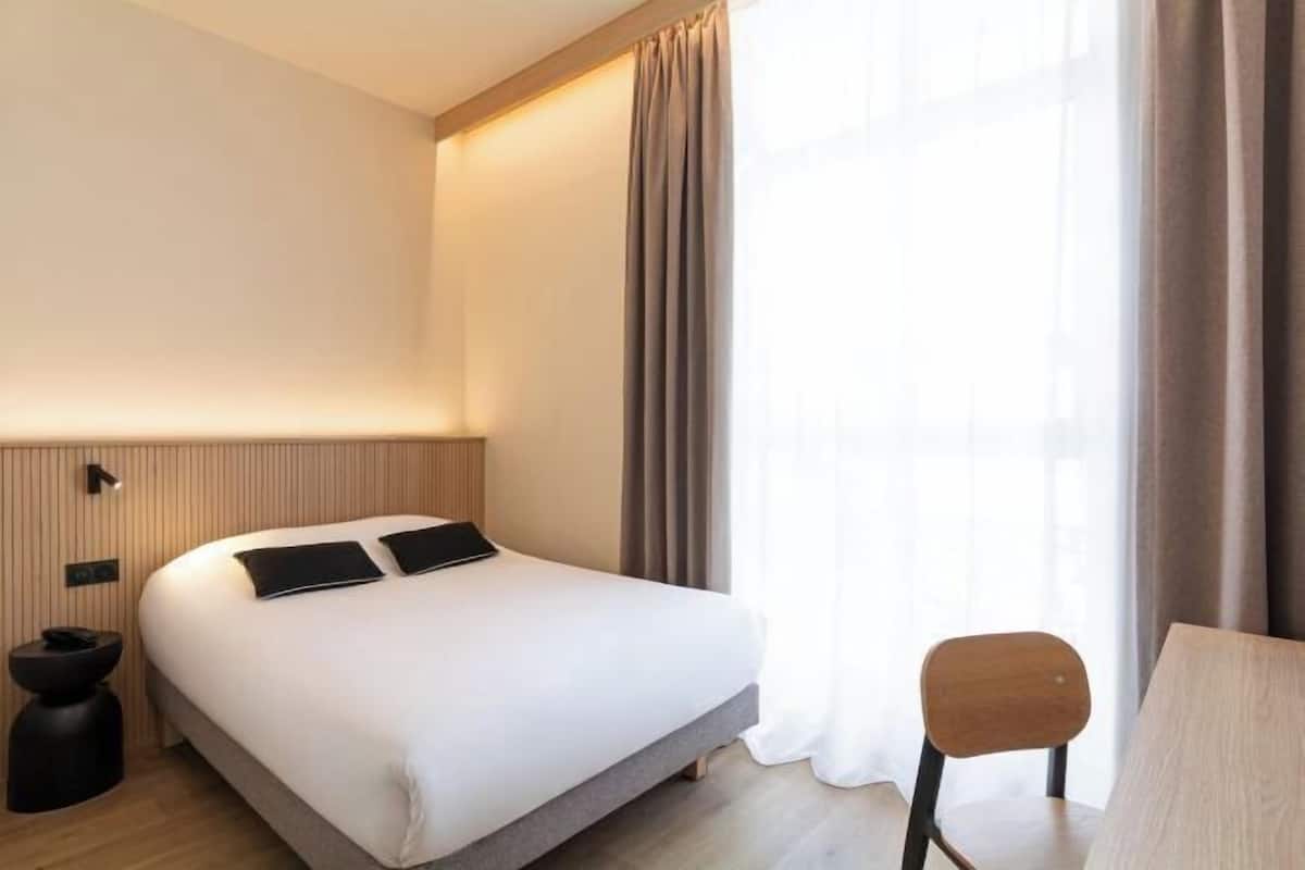 Een moderne hotelkamer met een groot bed, een bureau en een stoel.