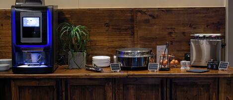 A breakfast bar with a coffee machine, a plant, and various breakfast items.
