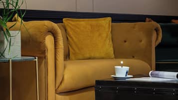 Una sala de estar moderna con un sofá color mostaza, una mesa de centro negra y una mesita auxiliar con una planta.