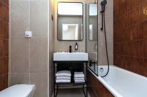 Un baño moderno con un lavamanos blanco, un espejo, una ducha y un inodoro.