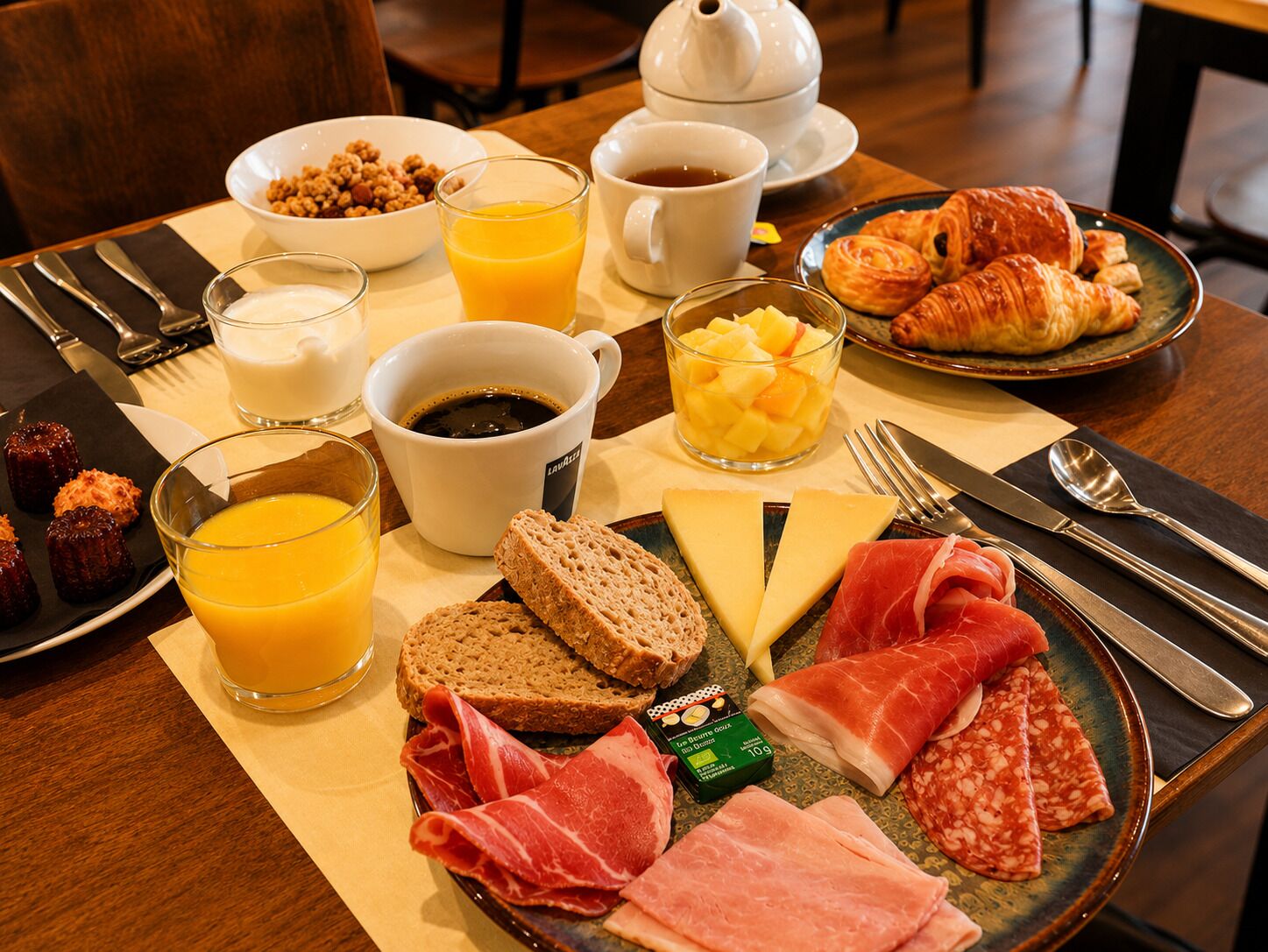 A breakfast setting with croissants, cheese, ham, and a fruit bowl.