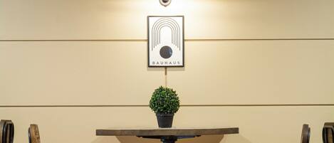 Una mesa con dos sillas, una planta pequeña en maceta y un logo enmarcado en la pared.