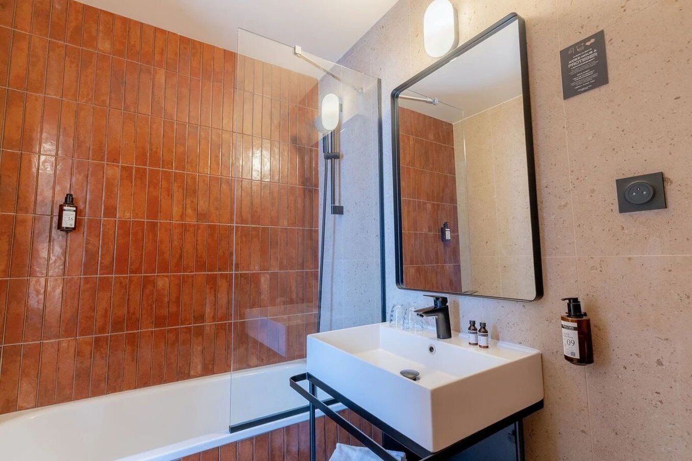 A modern bathroom with a white sink, a large mirror, and a shower enclosure.