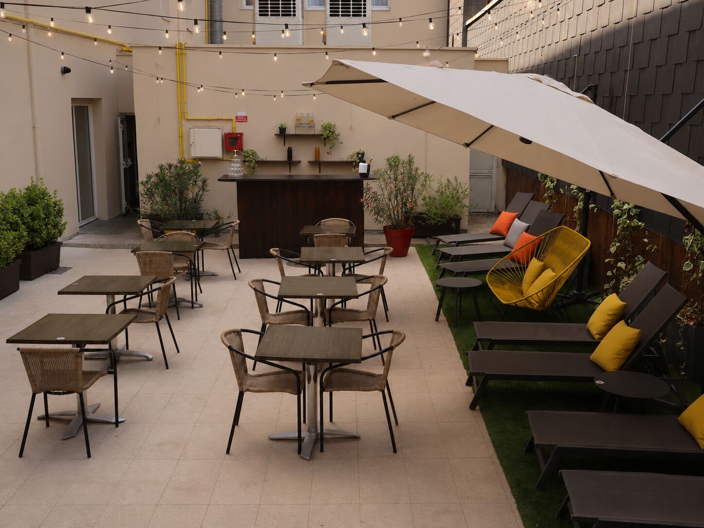 Un espacio al aire libre con mesas, sillas, un bar y plantas en macetas.