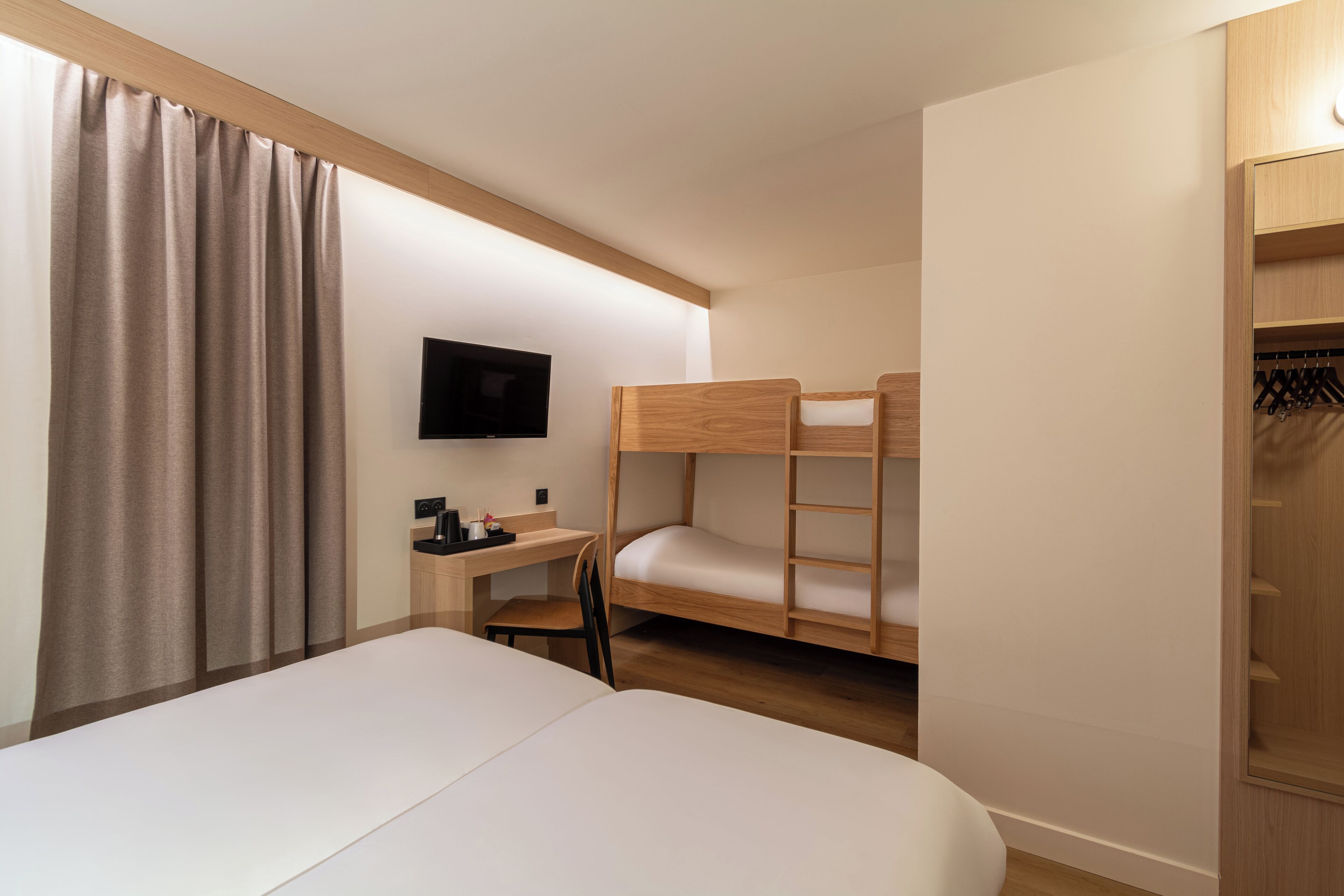 Une chambre avec un lit superposé, un bureau avec une chaise, une télévision et une armoire.