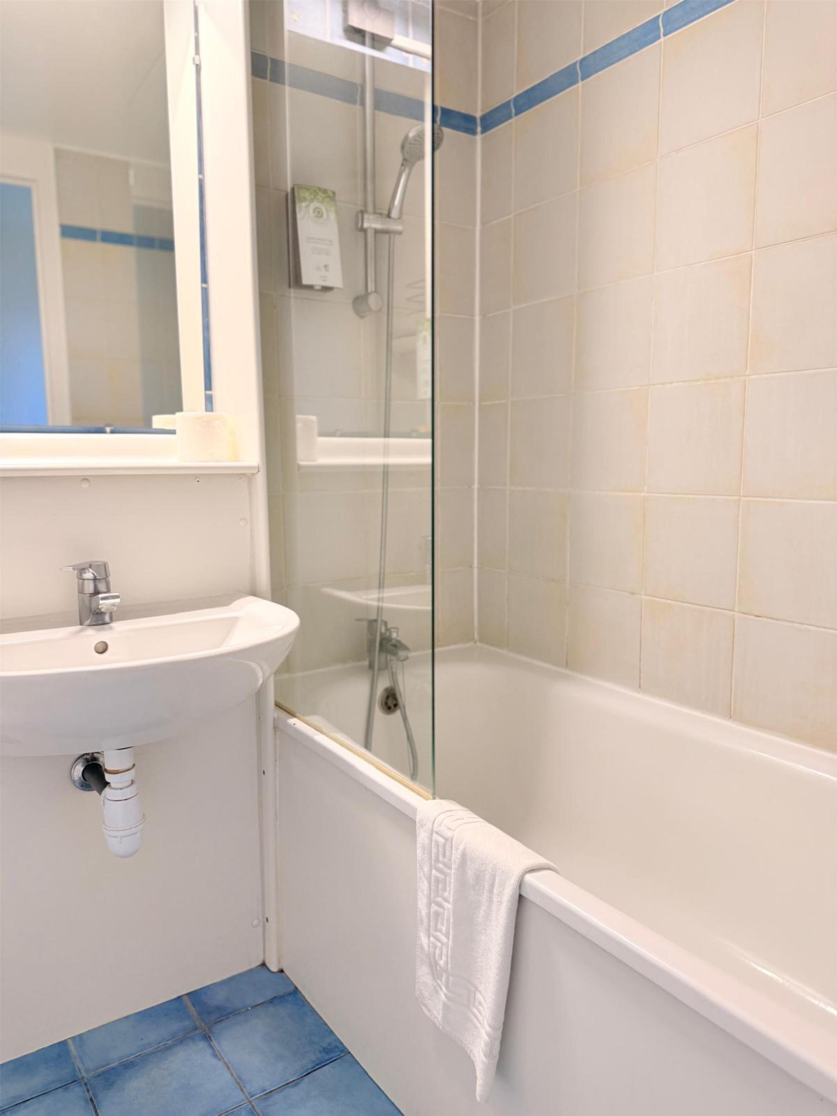 A bathroom with a white sink, a glass shower enclosure, and a bathtub.