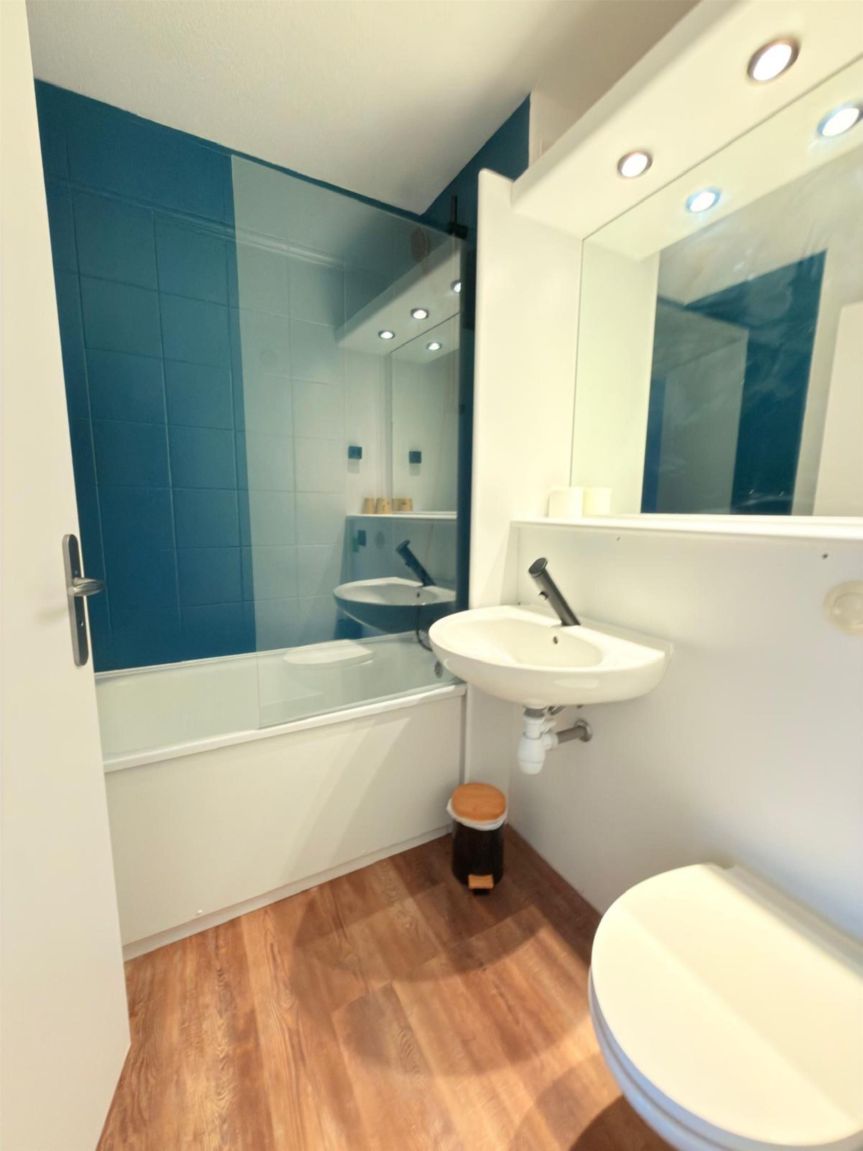 A modern bathroom with a glass shower enclosure, a white sink, and a toilet.