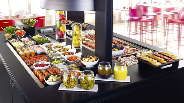 A buffet table with various food items and condiments. - Kyriad Blois Sud-Vineuil (Vineuil)