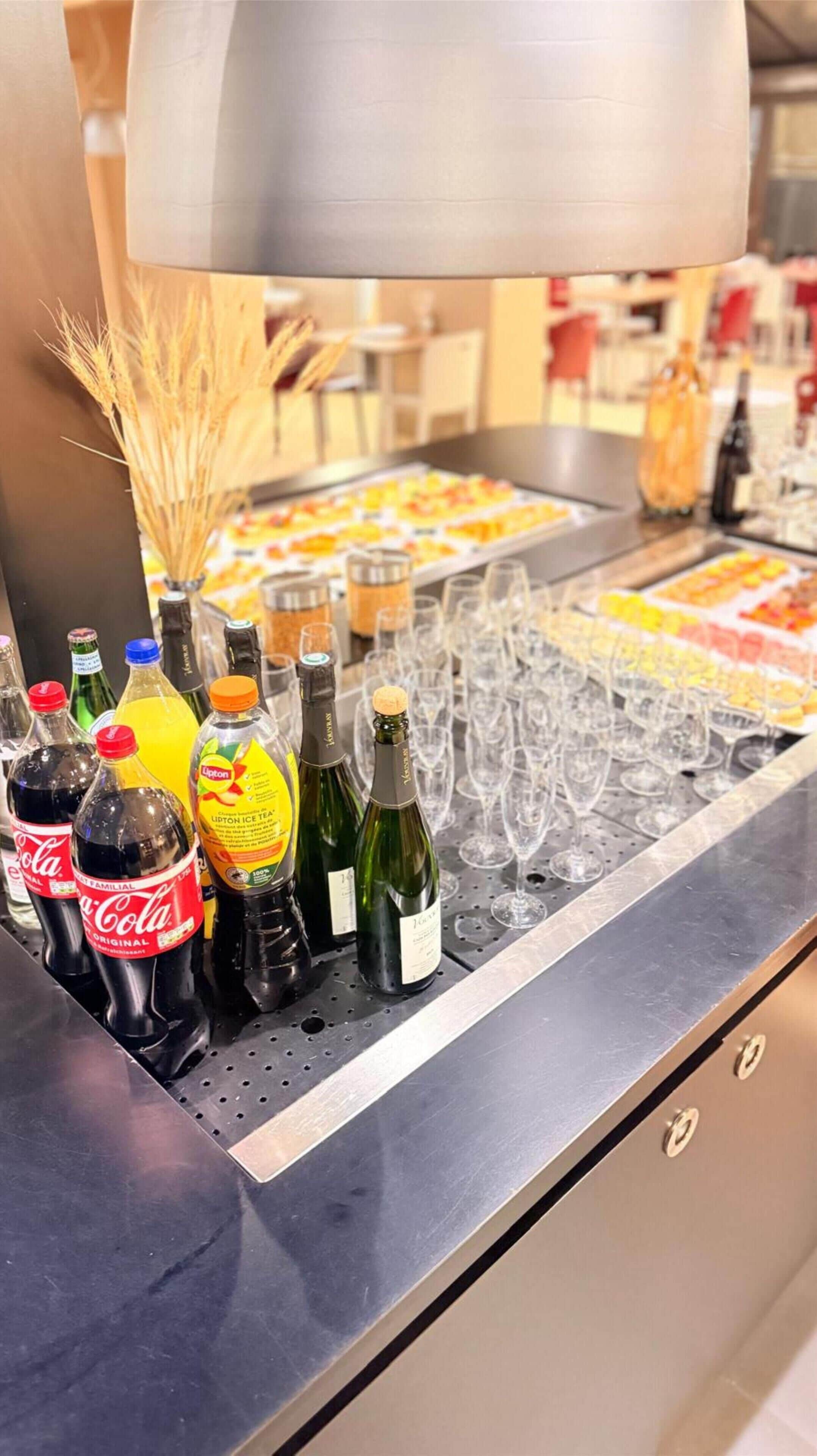 Ein Bereich mit einem Buffet, verschiedenen Getränken, darunter Coca-Cola und Lipton Eistee, sowie einer Auswahl an Weingläsern.