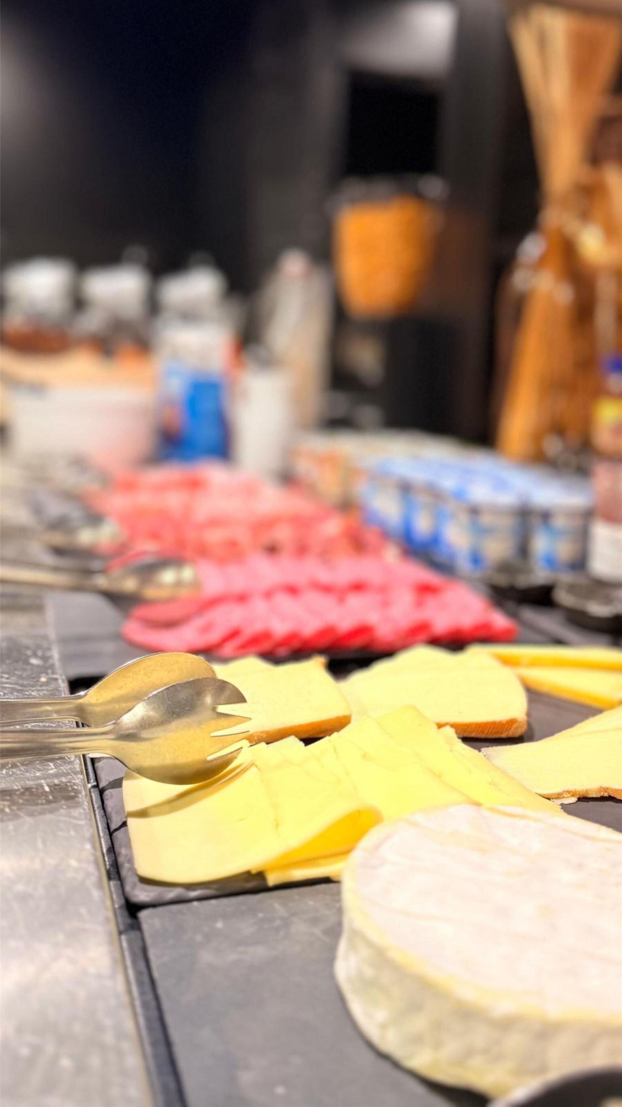 Een kaasplank met verschillende soorten kaas en een lepel.