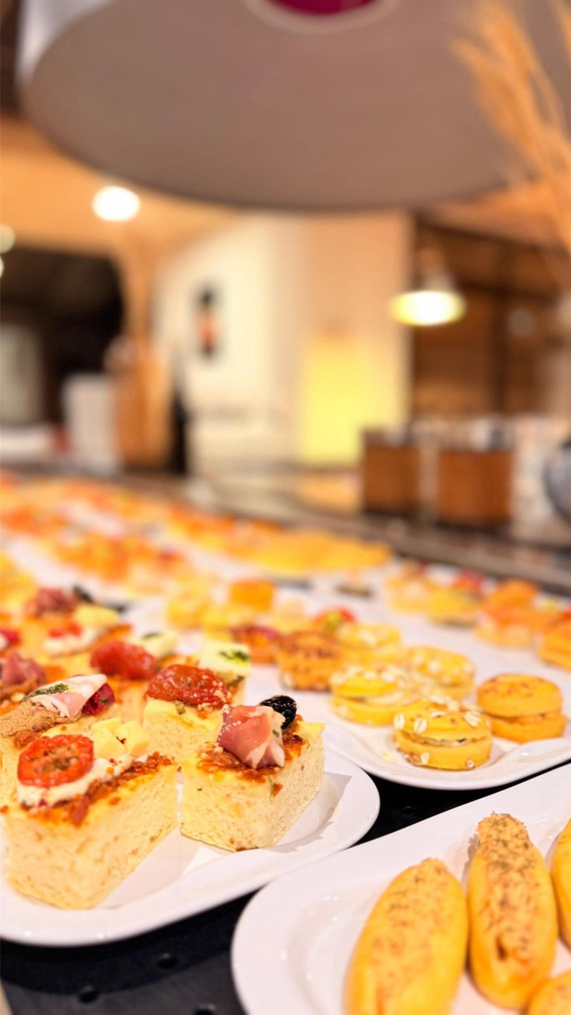 Un buffet con diversi piatti, tra cui pane, formaggio e piccoli pasticcini.