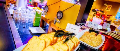 A buffet with various food items and a beverage station.