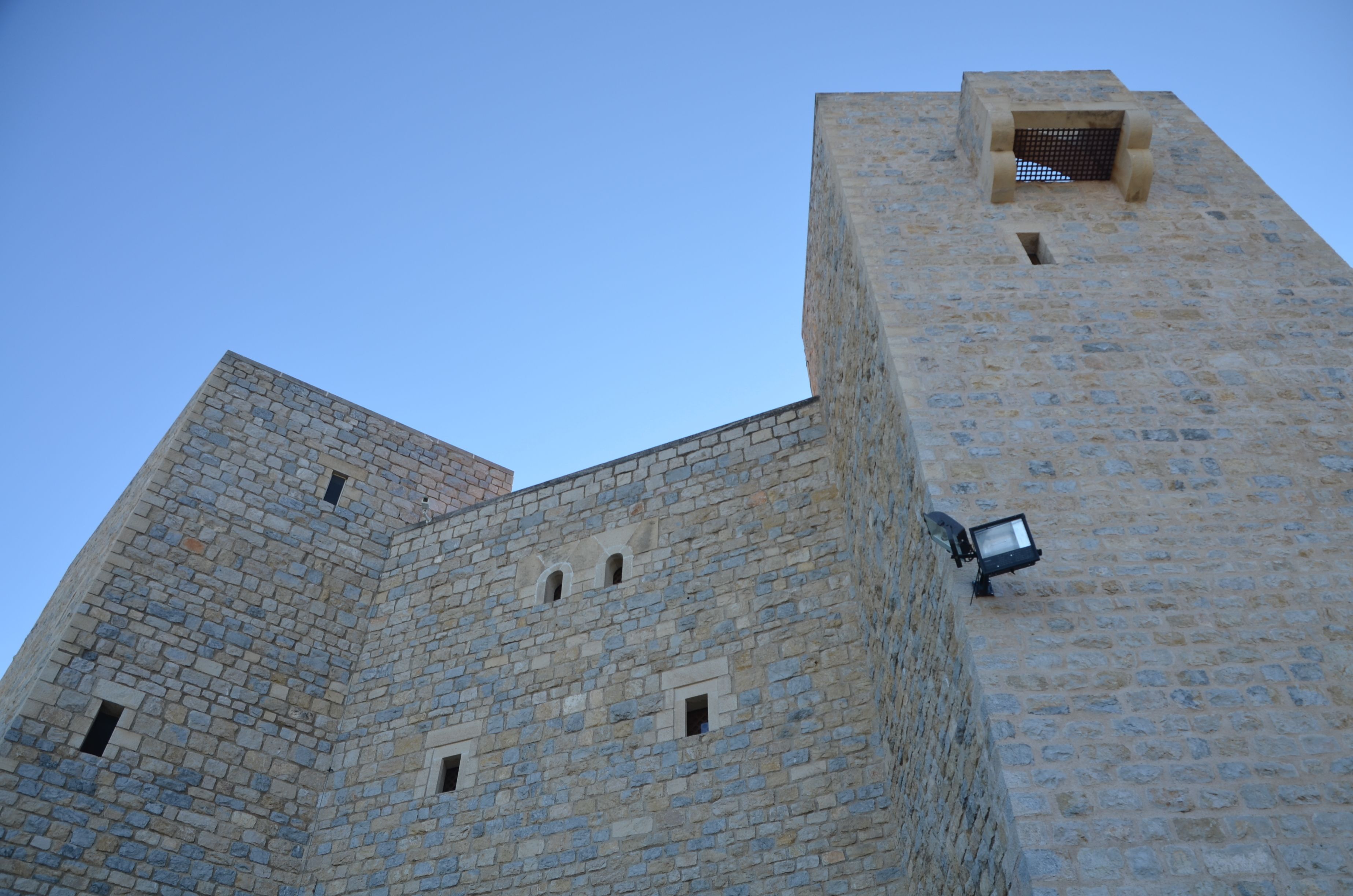 A tall stone building with a square tower and a smaller square section on top.