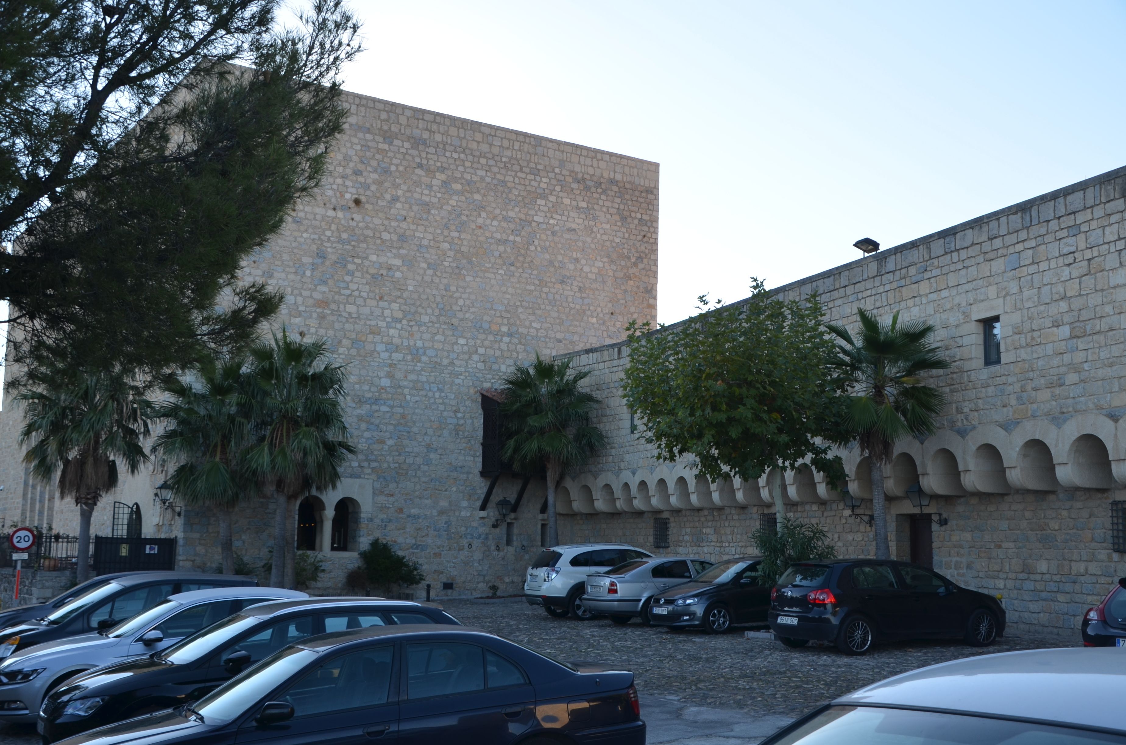 A stone building with parked cars in front.