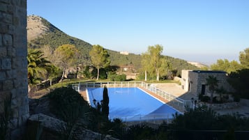 Una piscina al aire libre de temporada, sombrillas