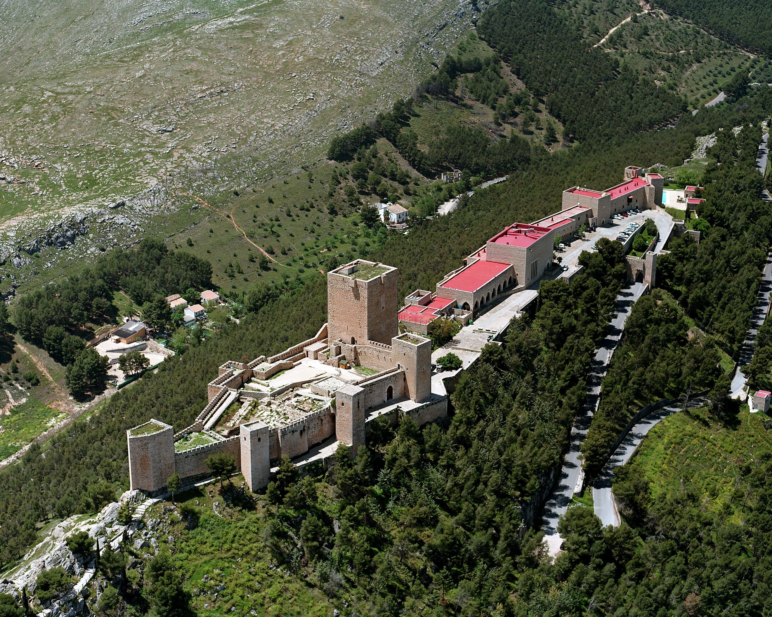 Vista aérea de un complejo de castillos históricos con múltiples torres, rodeado de un bosque denso y un río.