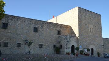 A stone building with a prominent tower, arched entrances, and potted plants.