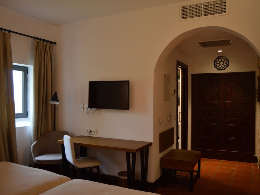 Une chambre d’hôtel équipée d’un lit, d’un bureau, d’une chaise, d’une télévision et d’une porte ornée d’un panneau décoratif.