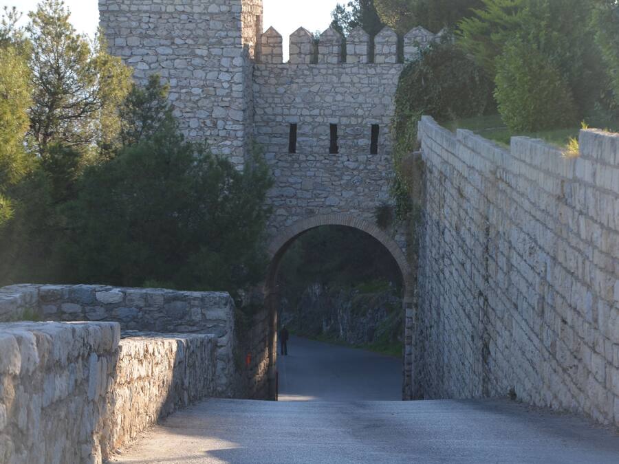 A stone bridge leading to a castle with battlements.