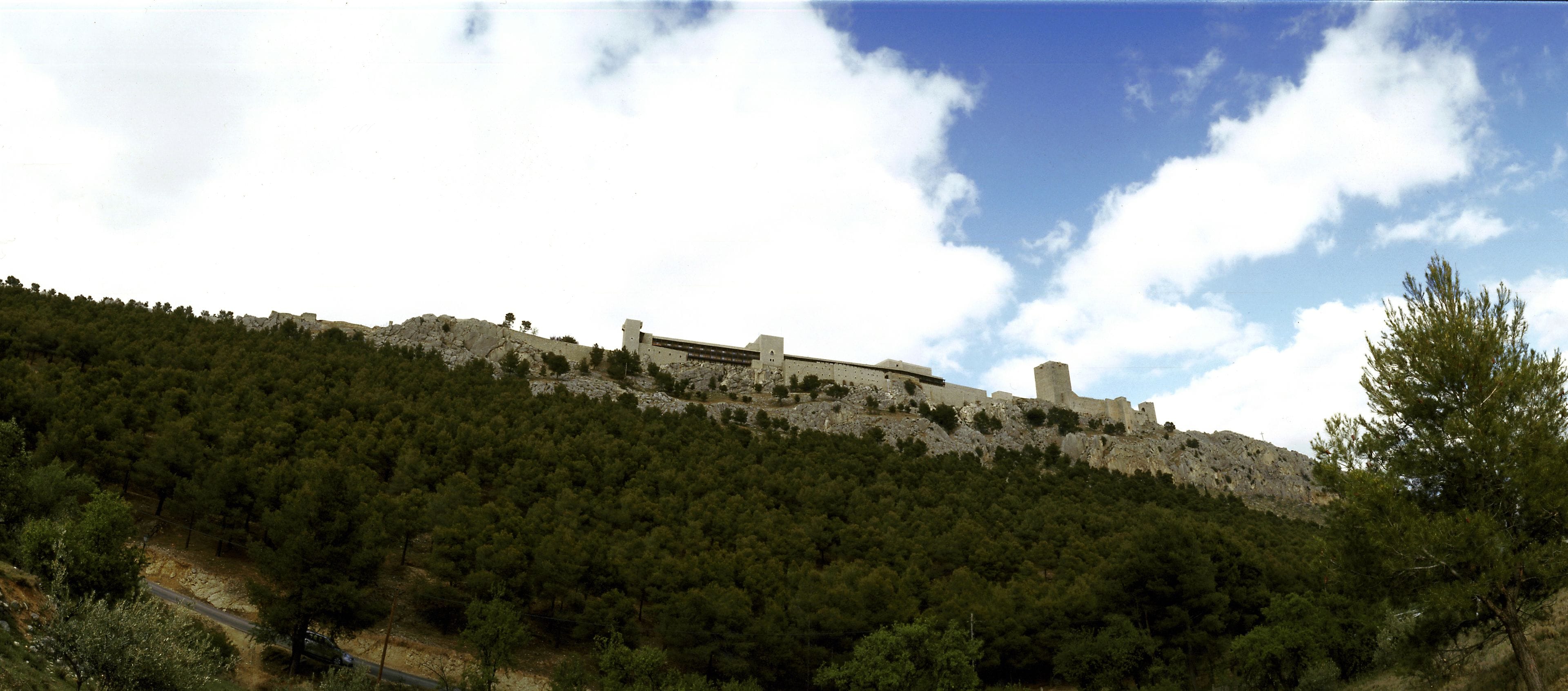 A historic building on a hill with dense forest.