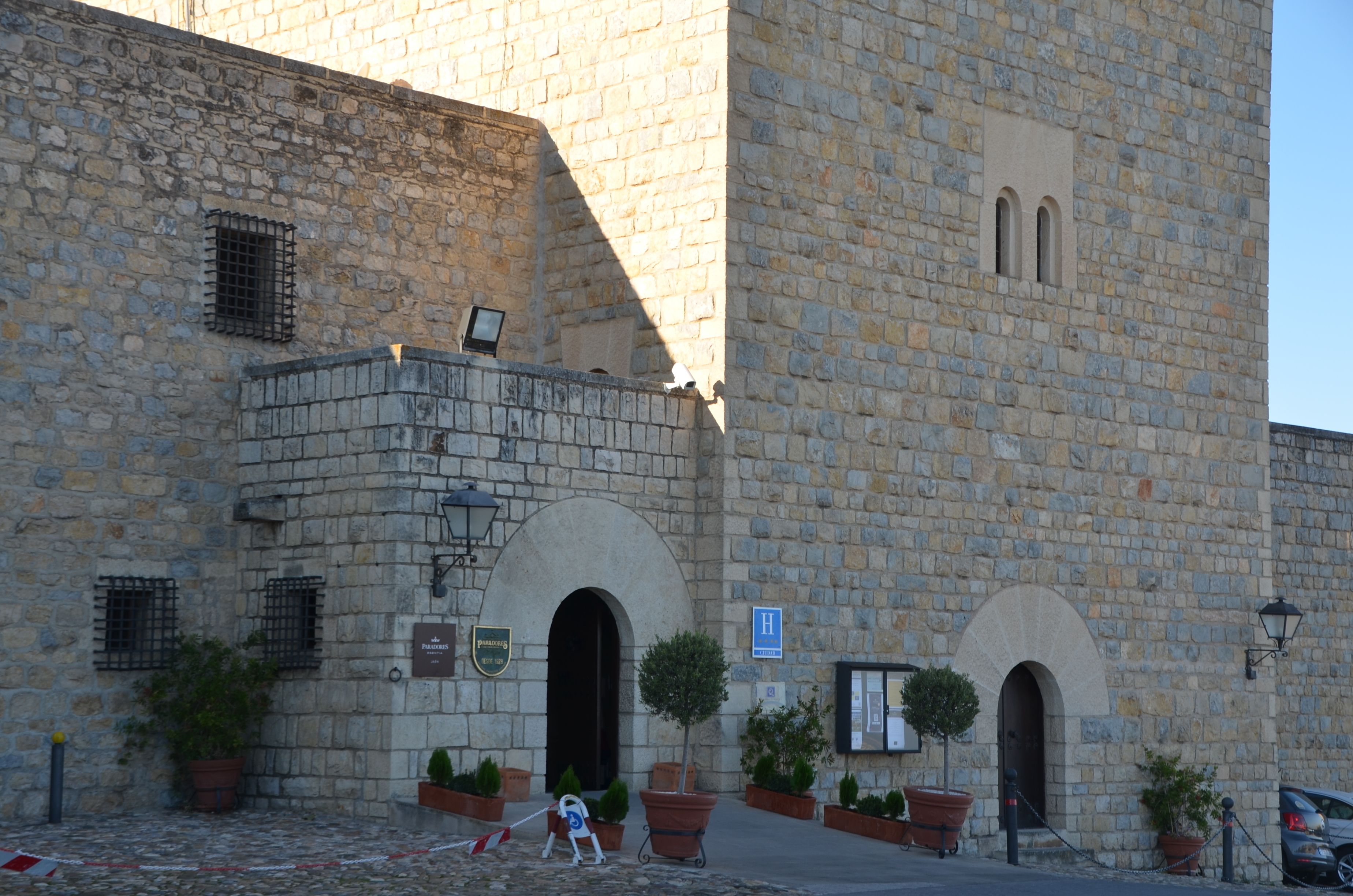 A stone building with a sign indicating a hotel. There are potted plants and a small sign for a restaurant.