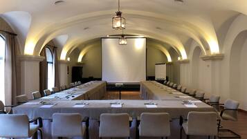 A conference room with a long table, chairs, and a projector screen.