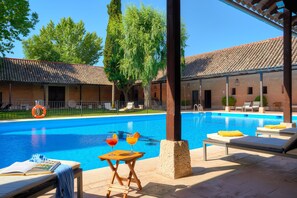 Una piscina al aire libre, sillones reclinables de piscina