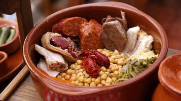A terracotta bowl filled with various meats and vegetables.