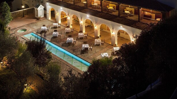 Un edificio histórico con un patio, asientos al aire libre y una piscina.