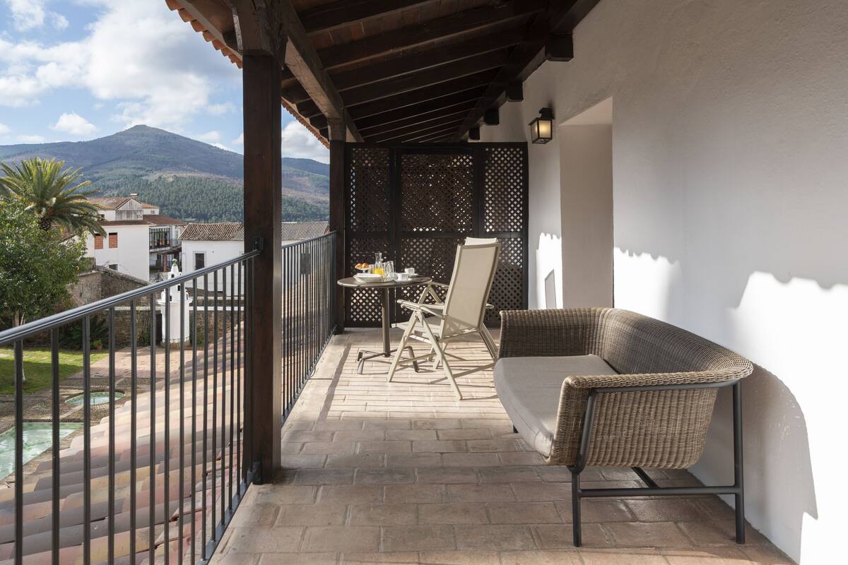 Un balcon avec un canapé en osier, une table et une chaise, et une vue sur une montagne.