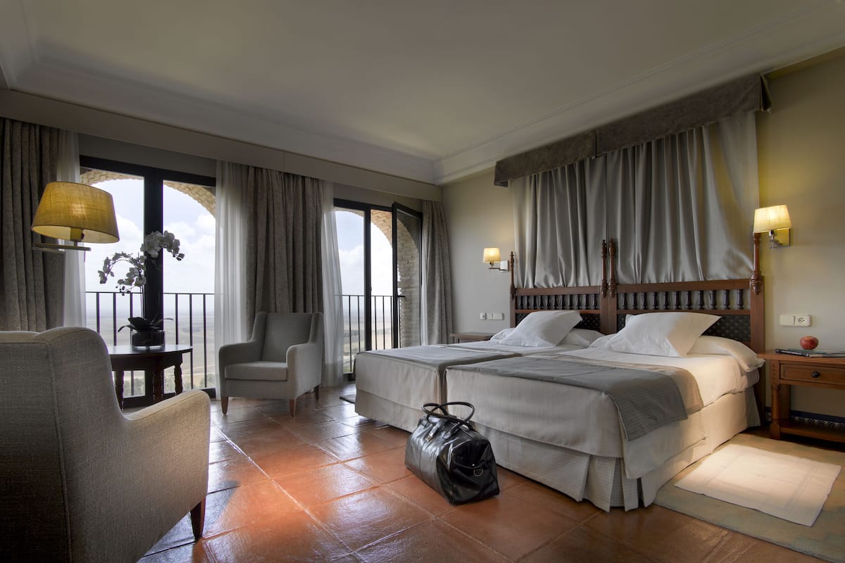 Une chambre d’hôtel avec un lit, une chaise, une table et une vue sur l’extérieur.