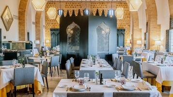 Un restaurante con techos altos de arco, lámparas colgantes hexagonales y mesas dispuestas para comer.
